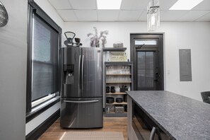 A modern kitchen with a stainless steel refrigerator, a built-in wine rack, and a granite countertop.