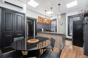 Une cuisine moderne avec un plan de travail noir, une table de salle à manger ronde entourée de chaises et un luminaire décoratif suspendu au-dessus du plan de travail.