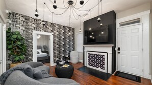 Een moderne woonkamer met een open haard, grijze banken en een grote spiegel.