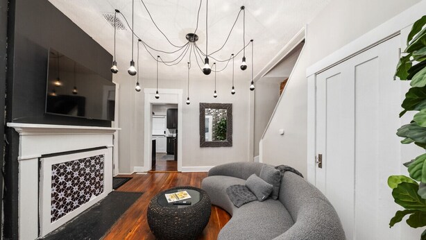 Een moderne woonkamer met een gebogen grijze bank, een ronde zwarte salontafel en een haard met een decoratief rooster.