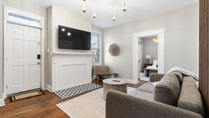 Una sala de estar moderna con chimenea, televisor de pantalla plana, una mesa de centro redonda y un espacio de descanso cómodo.