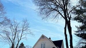 Kaksikerroksinen talo, jonka edessä on lumipeitteinen piha ja kivimuuri.