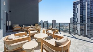 Eine Dachterrasse mit Außenbereich, Blick auf die Stadt und einem modernen Gebäude im Hintergrund.