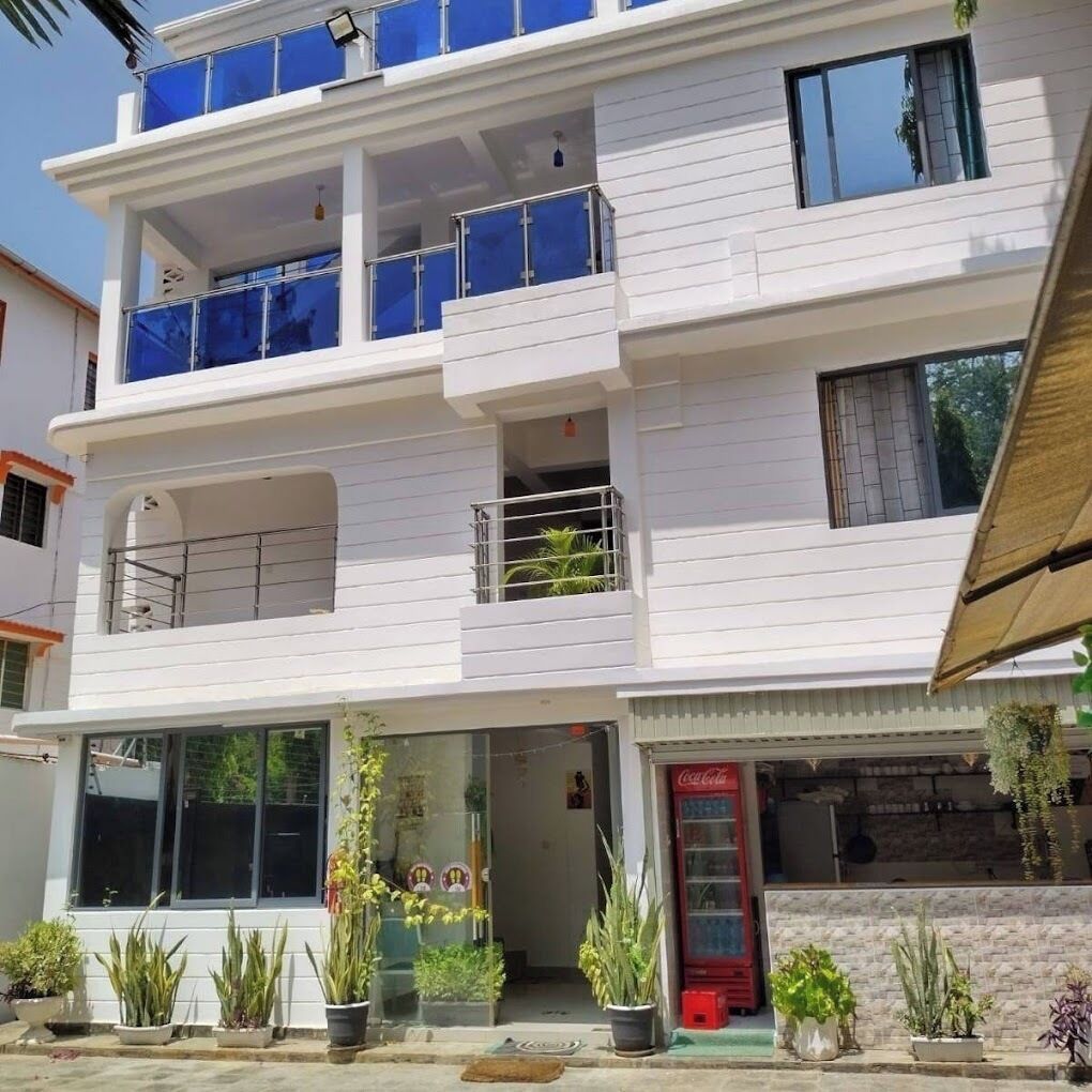 A multi-story building with balconies, a Coca-Cola refrigerator, and potted plants.