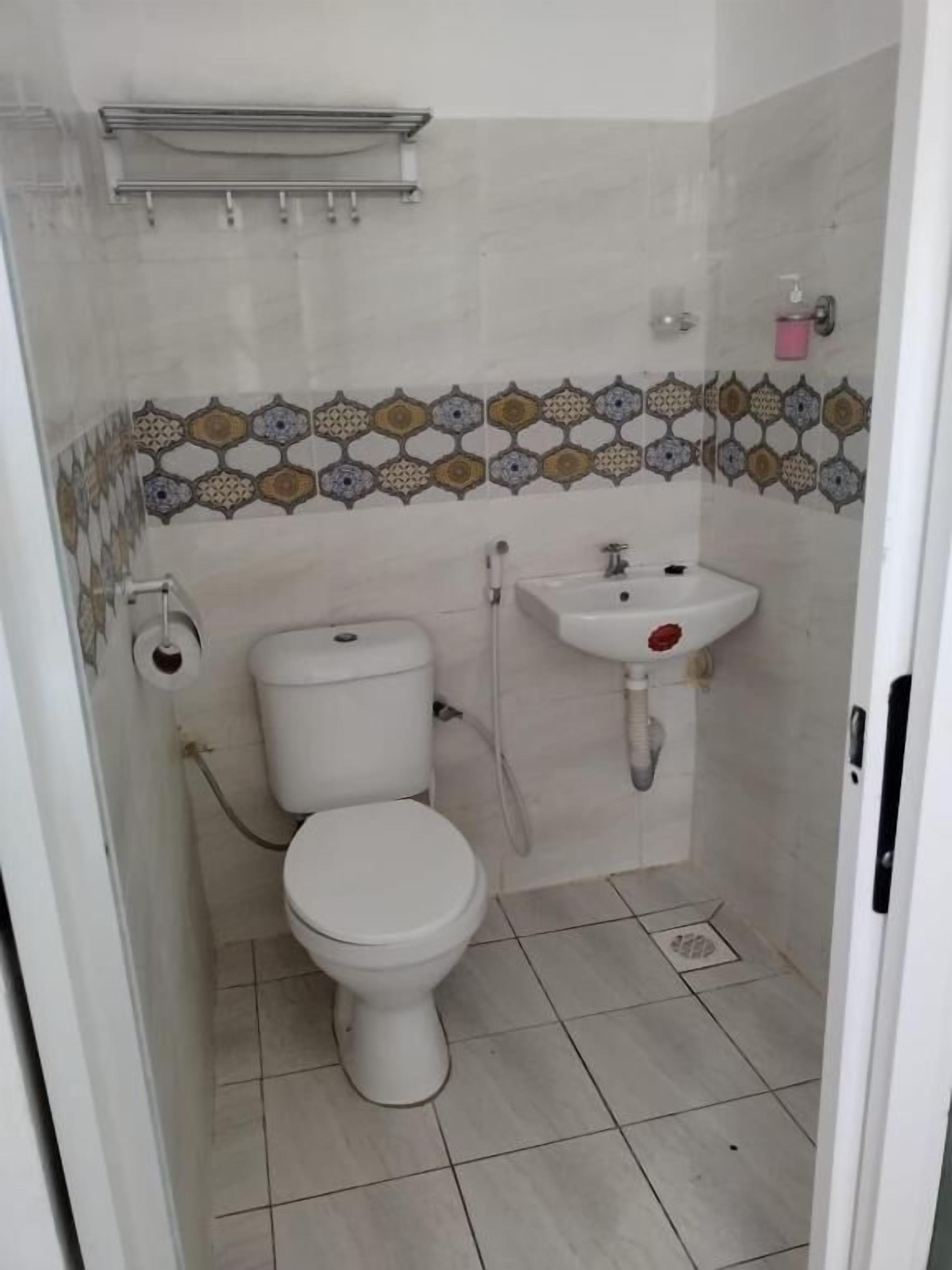 A small bathroom with a toilet, sink, and decorative tile backsplash.