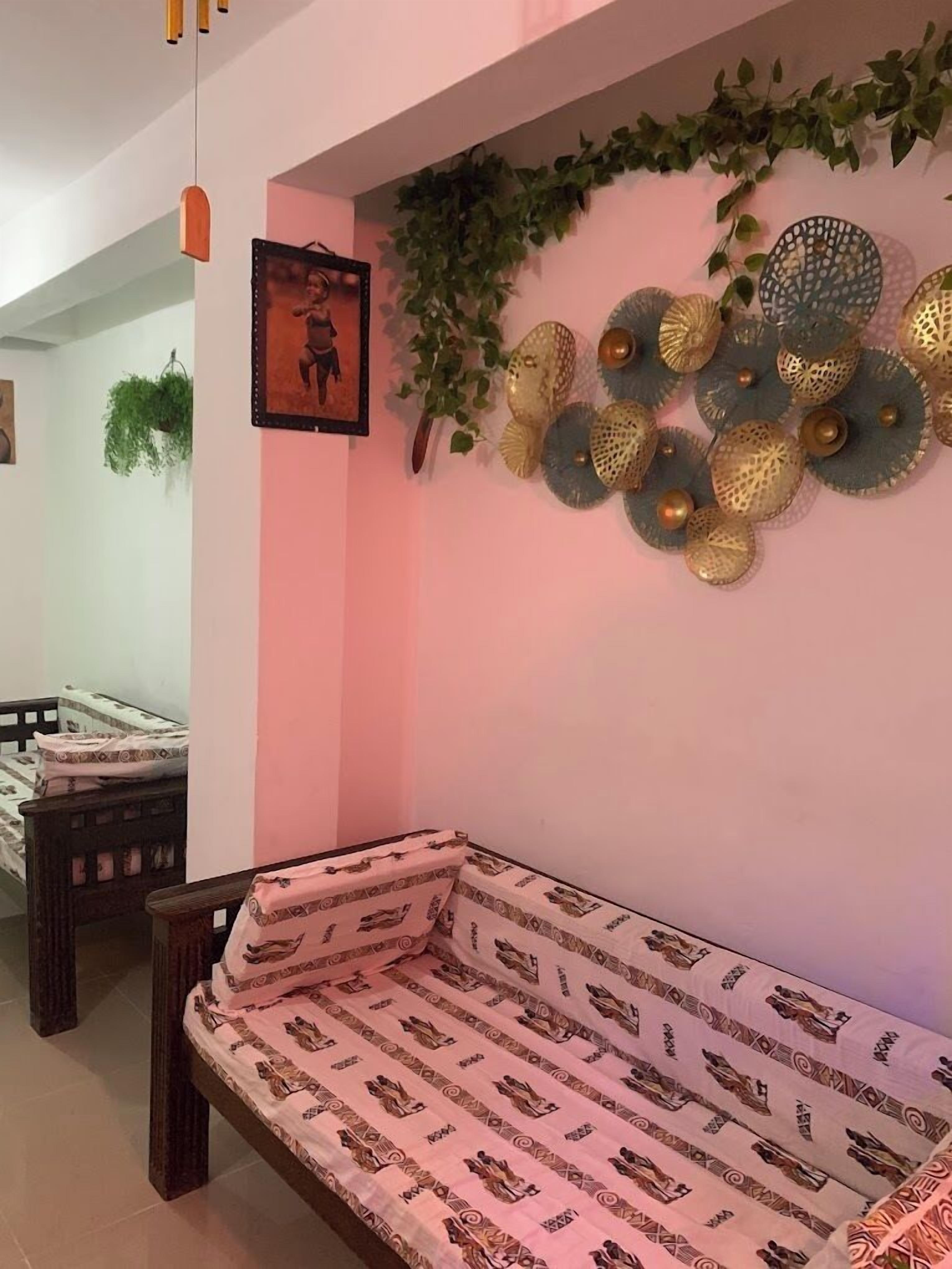 A room with a bed, a hanging plant, decorative wall art, and a hanging light fixture.