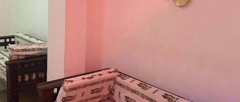 Una habitación con una cama, una planta colgante, decoración en la pared y una lámpara colgante.