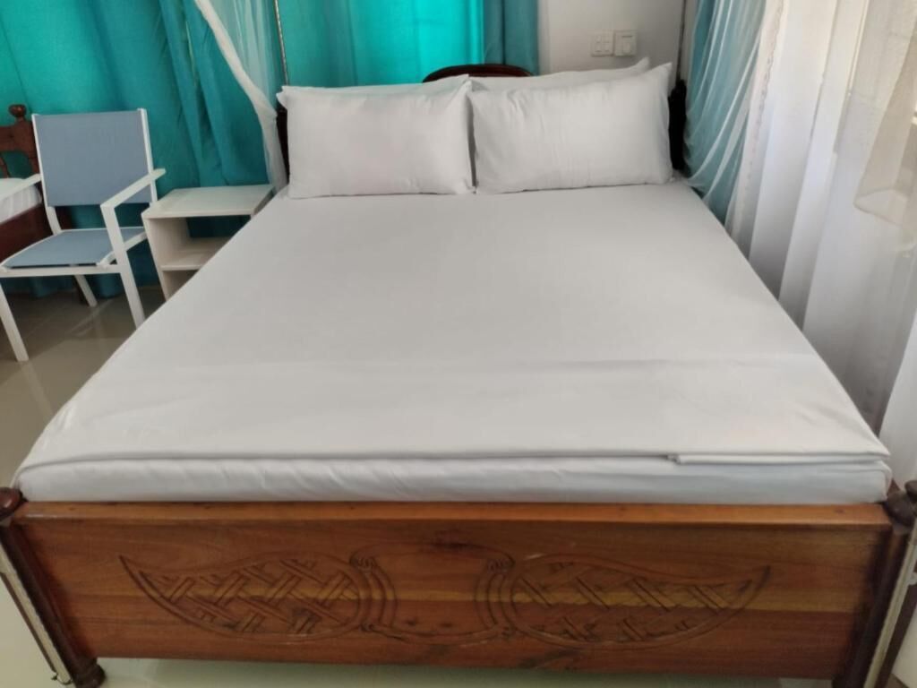 Una cama con estructura de madera y ropa de cama blanca.