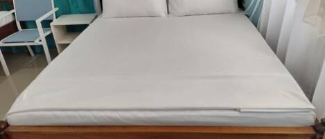 Una cama con estructura de madera y ropa de cama blanca.