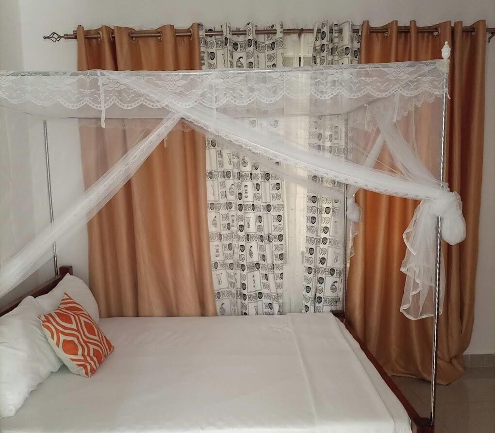 A bed with a canopy, brown curtains, and patterned curtains.