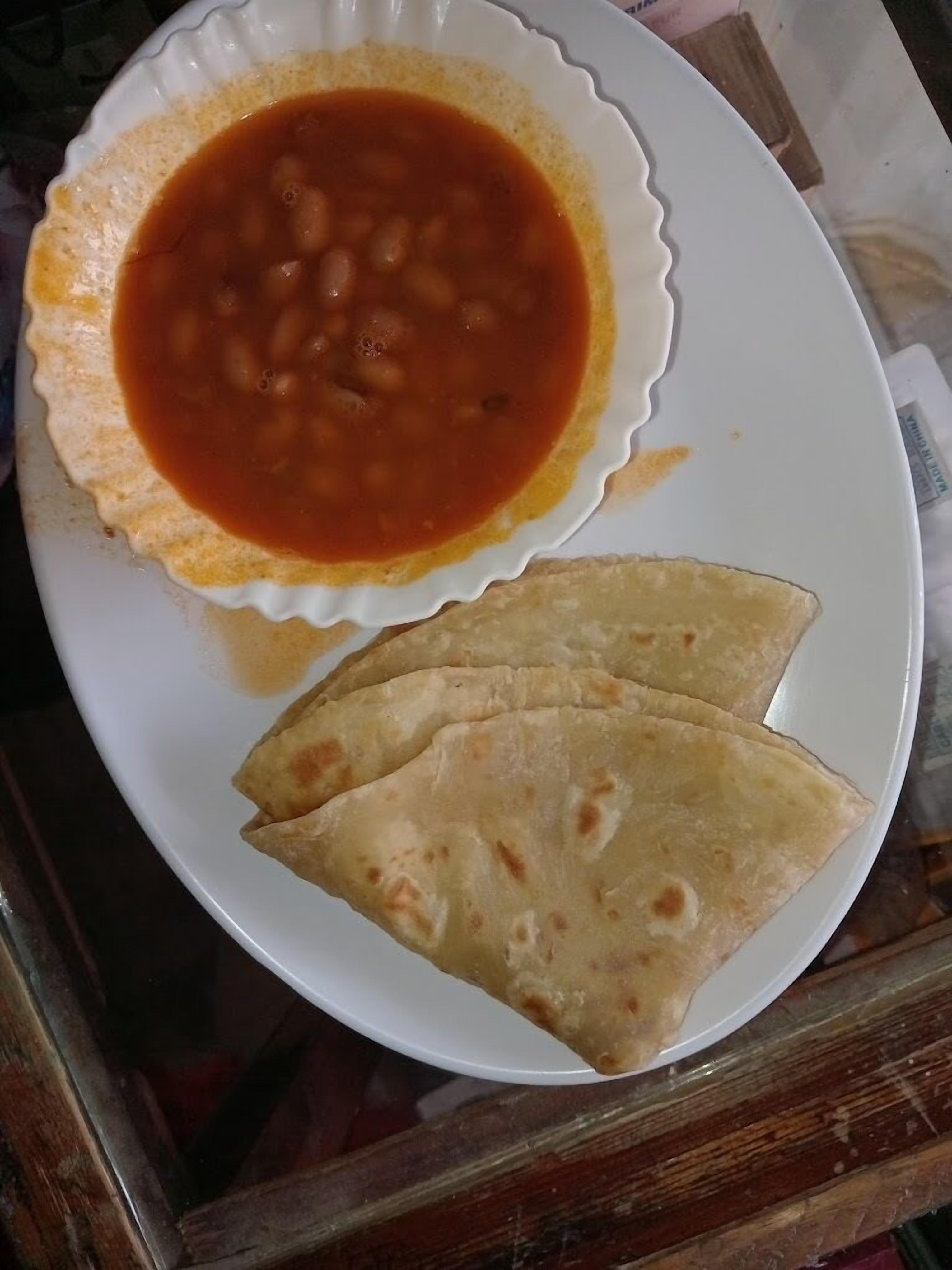 Un plato con un tazón de sopa y dos porciones de pan plano.