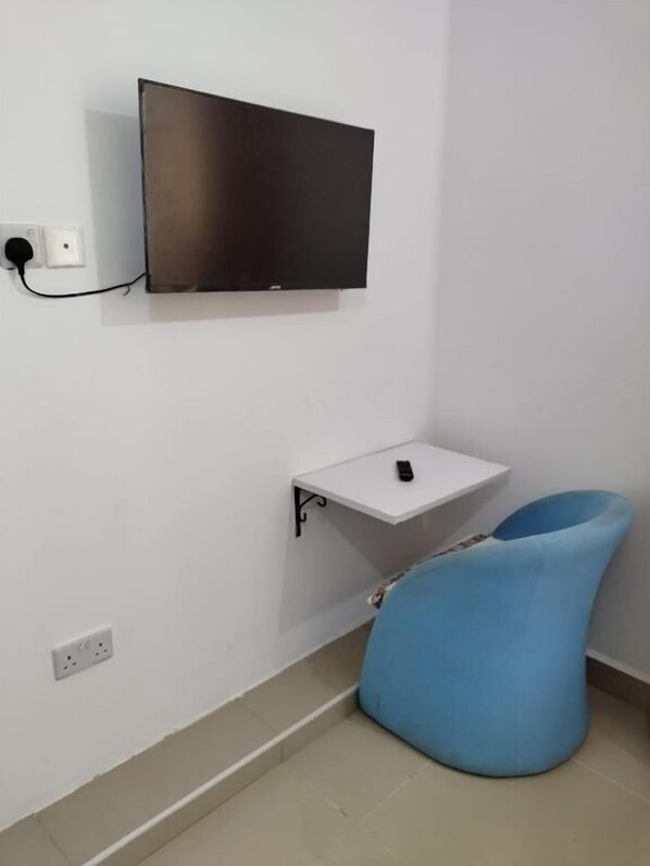 A room with a flat-screen TV mounted on the wall, a small white table with a remote control, and a blue bean bag chair. - 6 Park Retreat Mtwapa (Mtwapa)