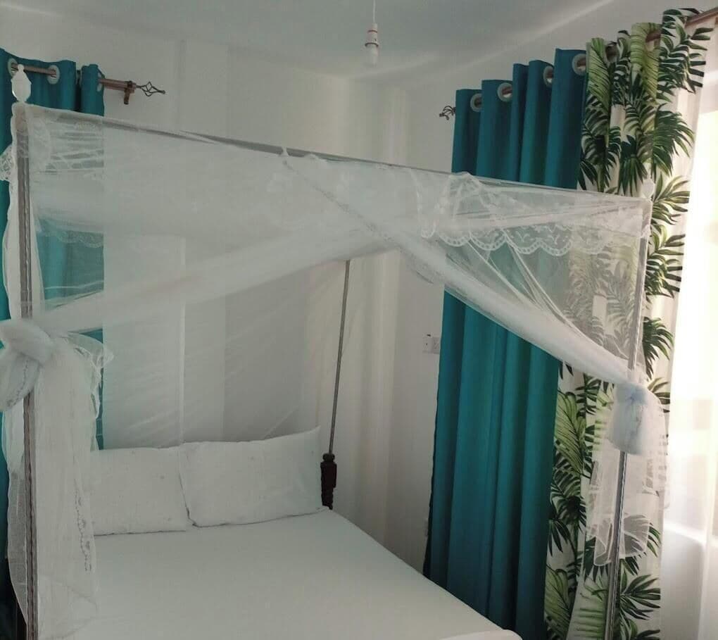 A bed with a white canopy and teal curtains.