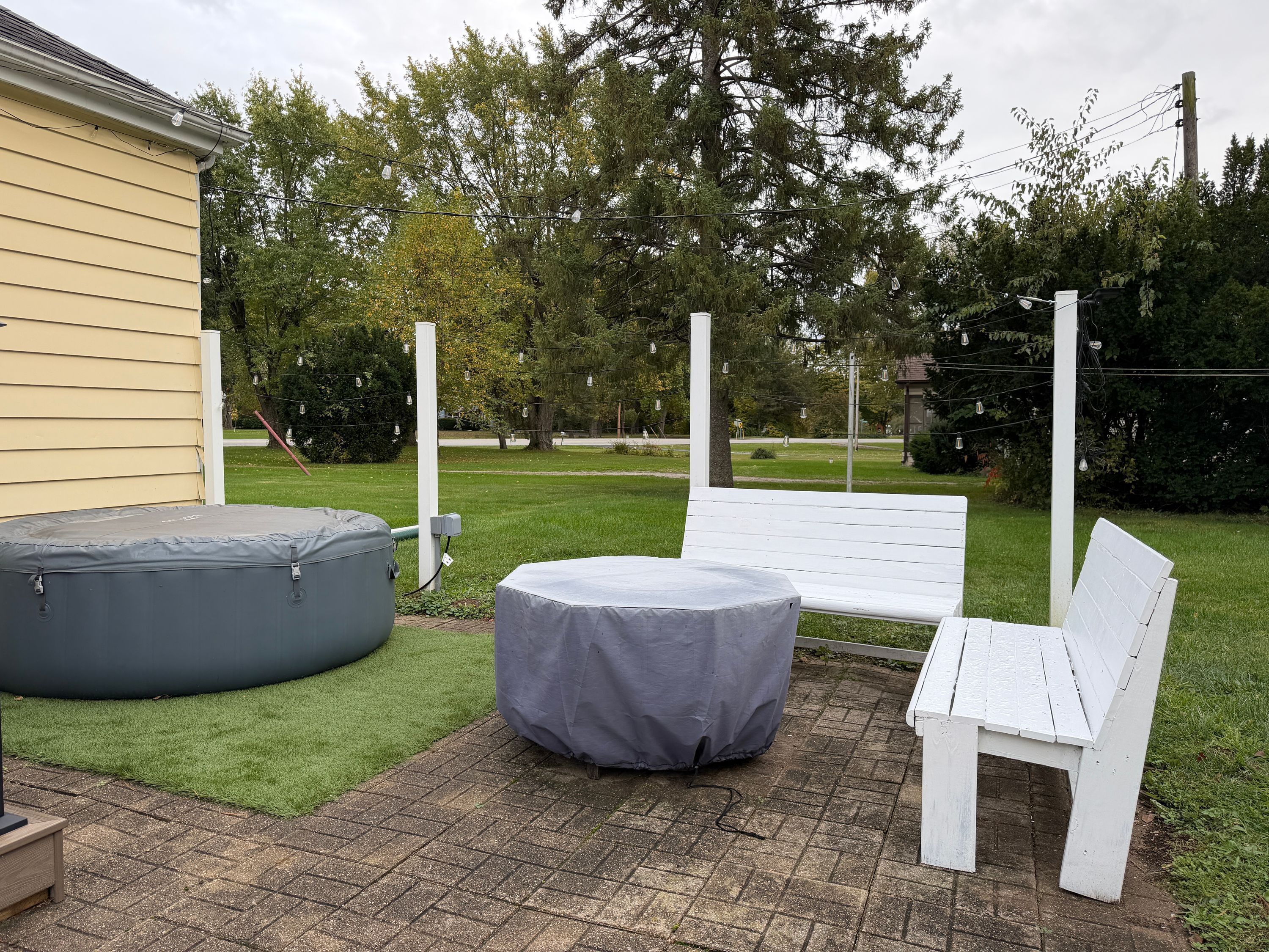 Un espace patio comprenant un banc blanc, un coin salon circulaire et une petite table.
