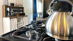 A kitchen with a gas stove, a kettle, and a coffee bar with coffee makers and bottles. - Hot Tub Outdoor Living Game Room Coffee Bar (South Bend)