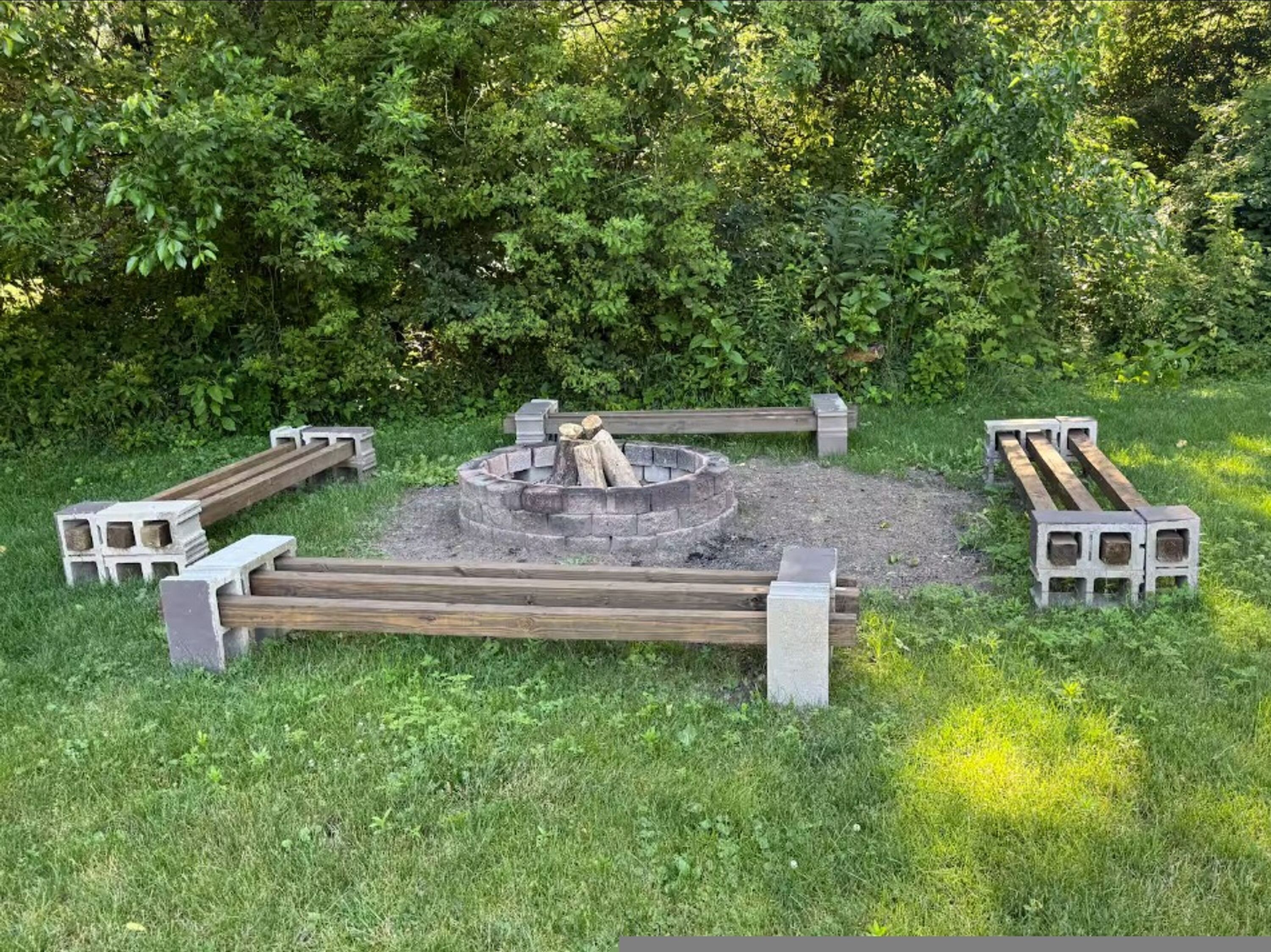 A circular fire pit surrounded by a wooden bench and concrete blocks.