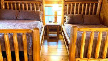 Une cabine équipée de deux lits superposés en bois, d’une petite table avec une lampe et d’un plancher en bois.
