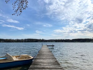 Une jetée en bois s’avance sur un lac paisible, et une petite embarcation est amarrée à son extrémité.