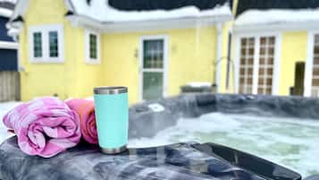 A hot tub with a yellow house in the background.