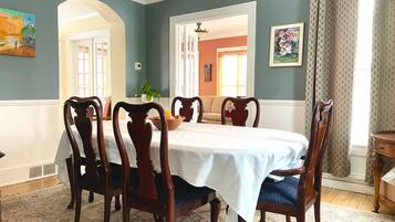 Comedor con una mesa redonda, seis sillas de madera y un mantel blanco.