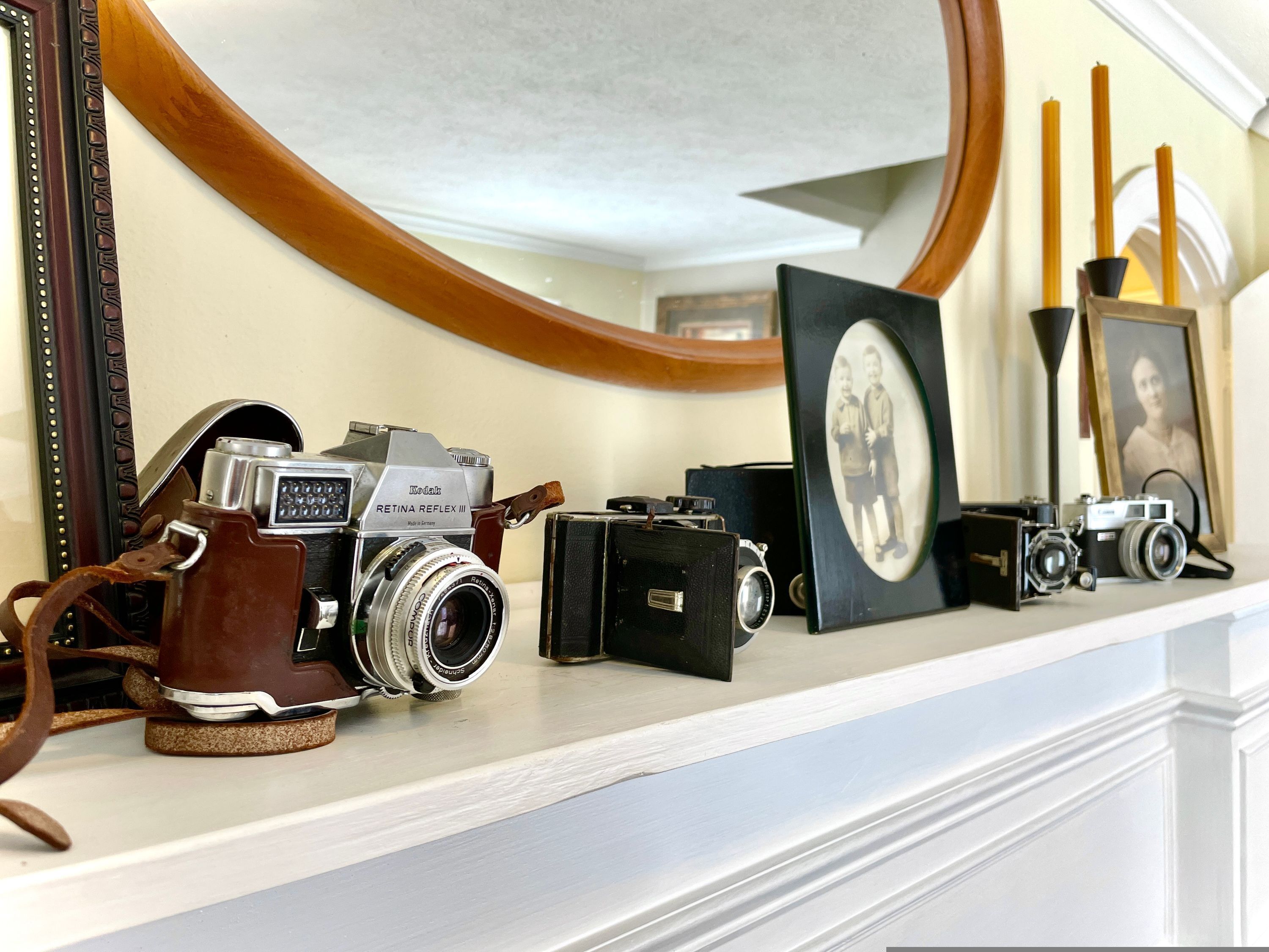 A collection of vintage cameras displayed on a mantelpiece.