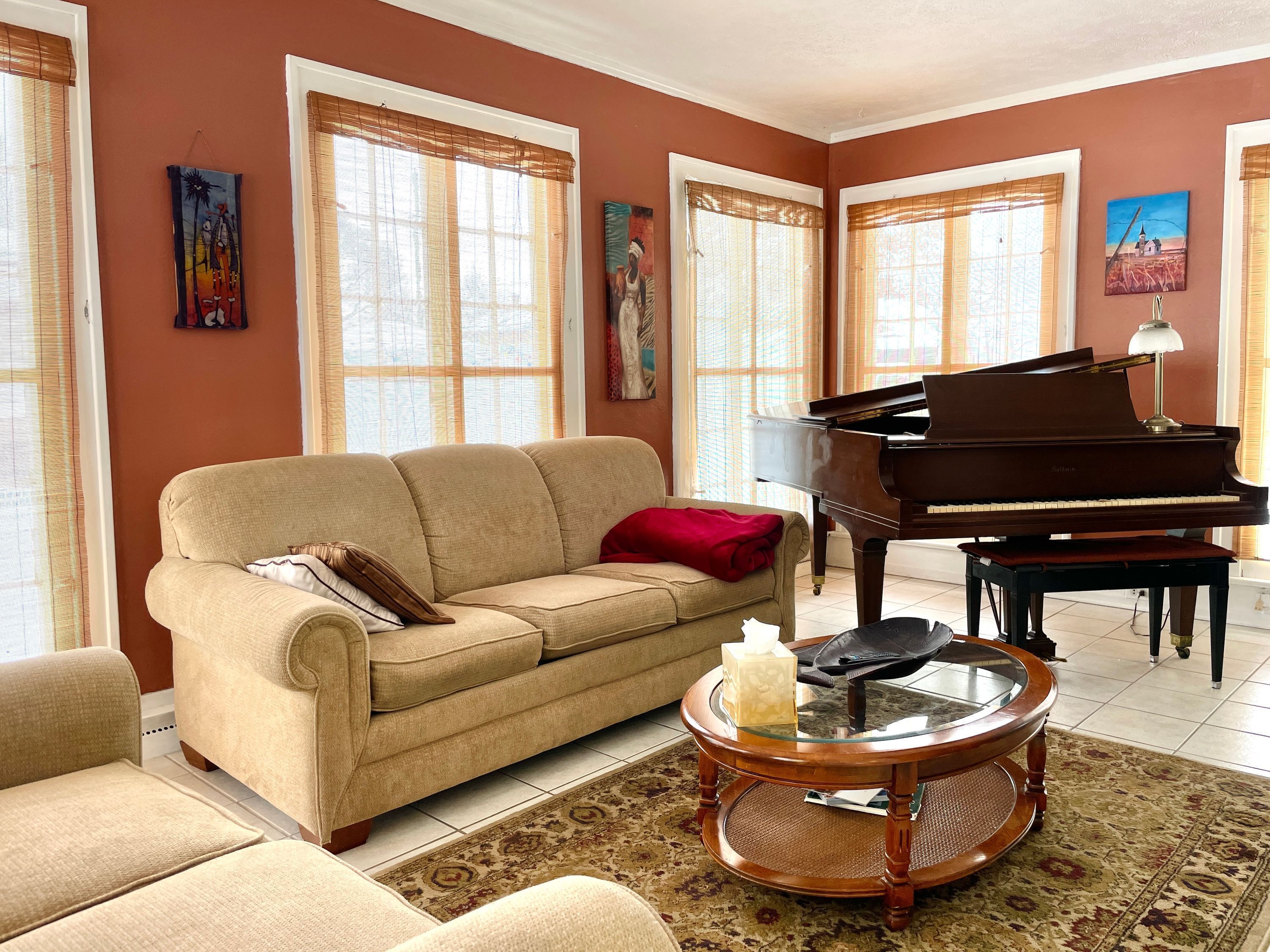 Un soggiorno con un divano beige, un pianoforte a coda e un tavolino da caff è in vetro.