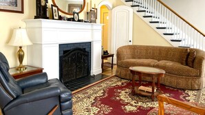 Un salon avec une cheminée, un canapé, un fauteuil et un escalier.