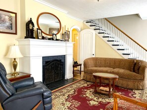 A living room with a fireplace, a sofa, a chair, and a staircase.
