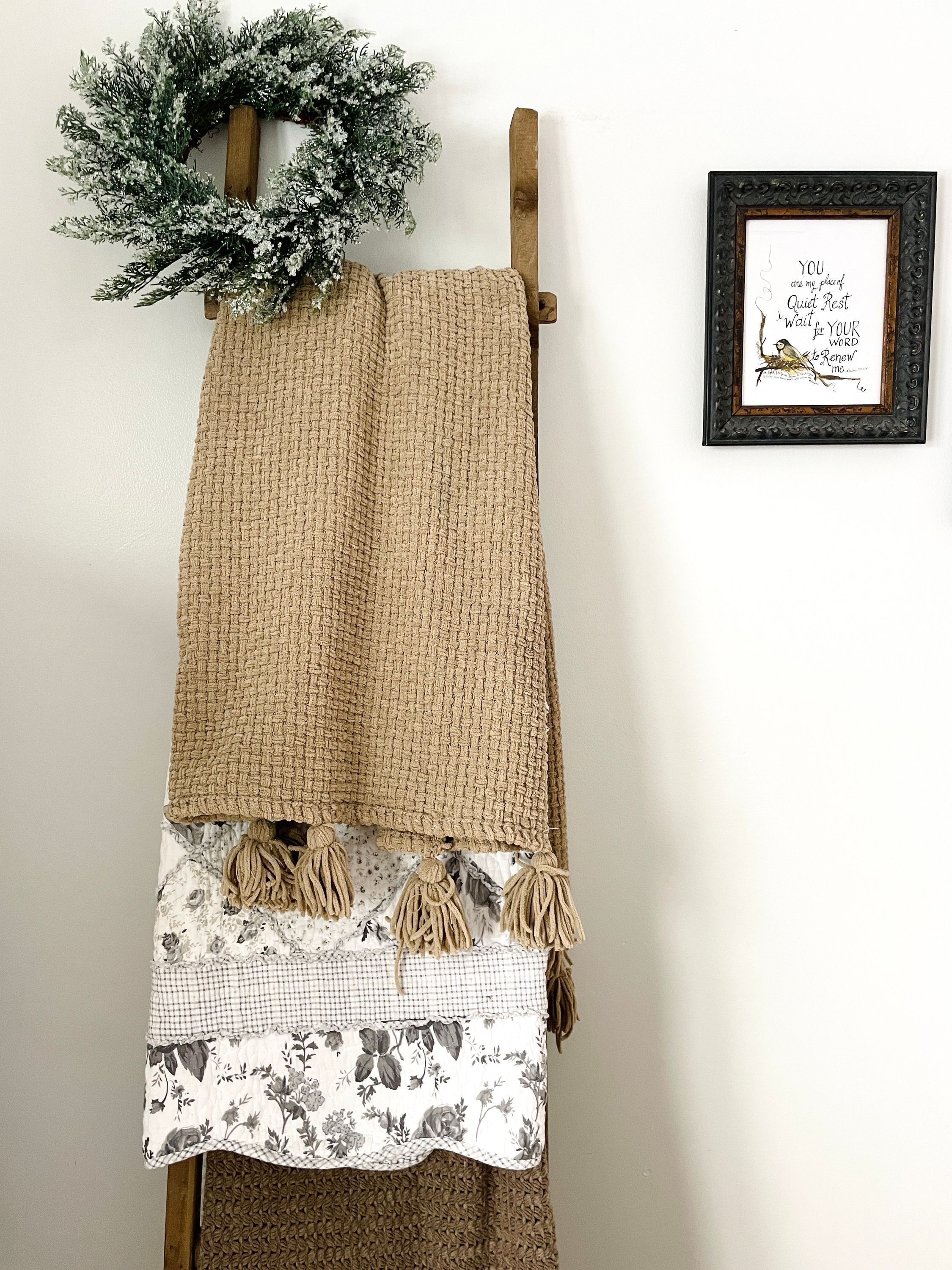 A wall-mounted wooden coat rack with a woven blanket and a floral-patterned garment.