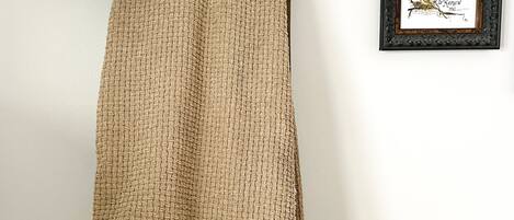 A wall-mounted wooden coat rack with a woven blanket and a floral-patterned garment.