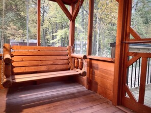 Un banc en bois sur une véranda, avec vue sur une forêt.