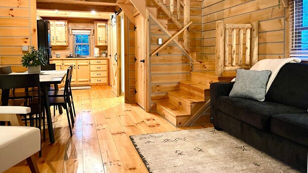 A wooden interior with a staircase, a dining area, and a living room. - Secluded Shipshewana Log Cabin In the Woods (Shipshewana)