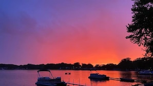 A sunset view of a lake with boats docked at a pier. - Lake Front Cottage Kayaks Game Table Fun (Shipshewana)