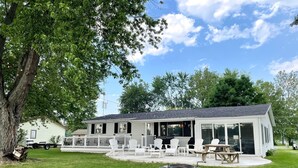 A modern house with a covered patio, outdoor seating, and a fire pit. - Lake House Kayaks Patio Deck Private Pier (Rome City)