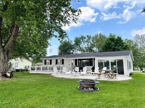 A modern house with a covered patio, outdoor seating, and a fire pit. - Lake House Kayaks Patio Deck Private Pier (Rome City)