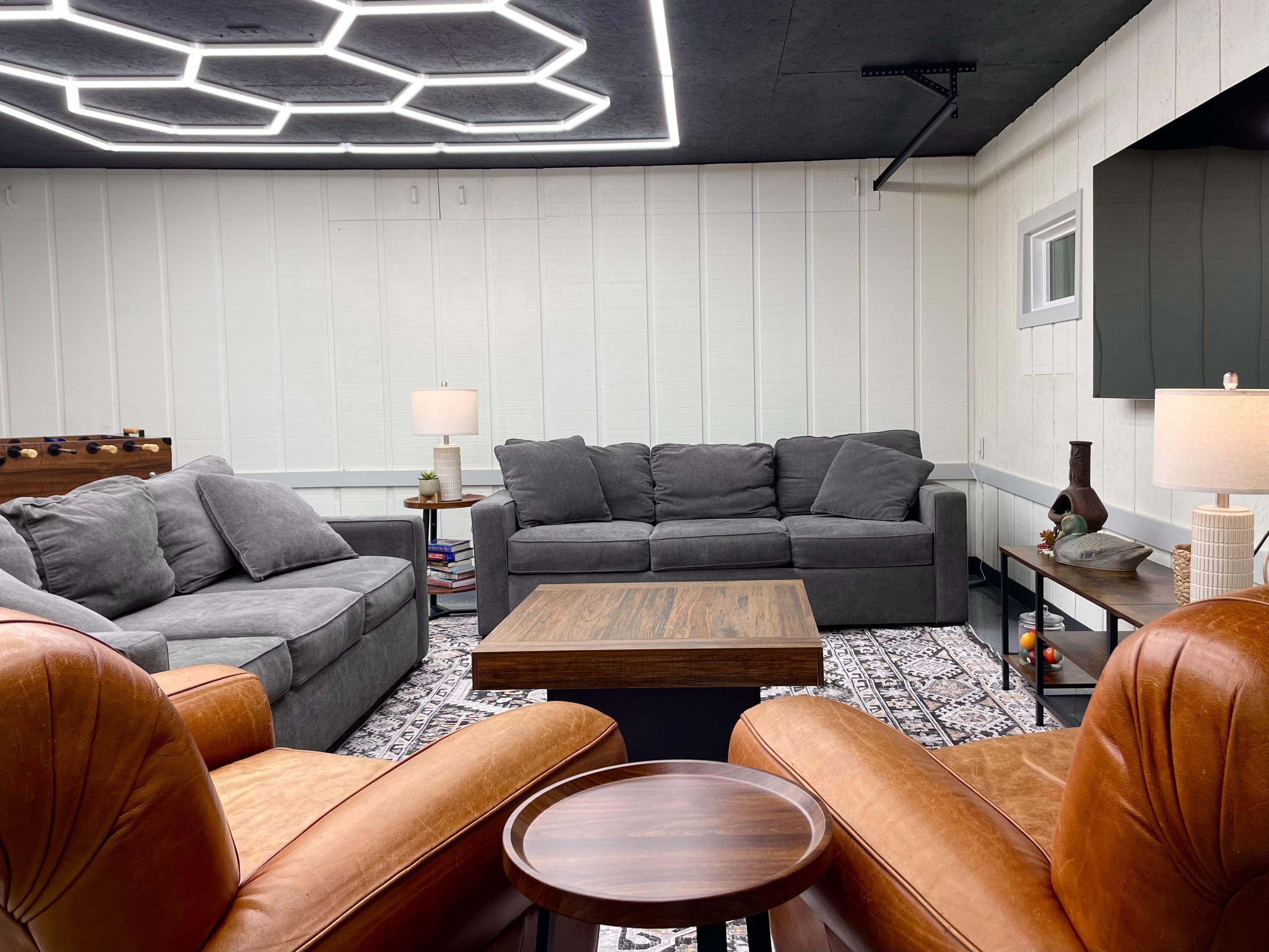A modern living room with a grey sectional sofa, a brown leather sofa, and a wooden coffee table.