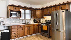 A modern kitchen with wooden cabinets, stainless steel appliances, and a marble countertop. - Lake House Kayaks Patio Deck Private Pier (Rome City)