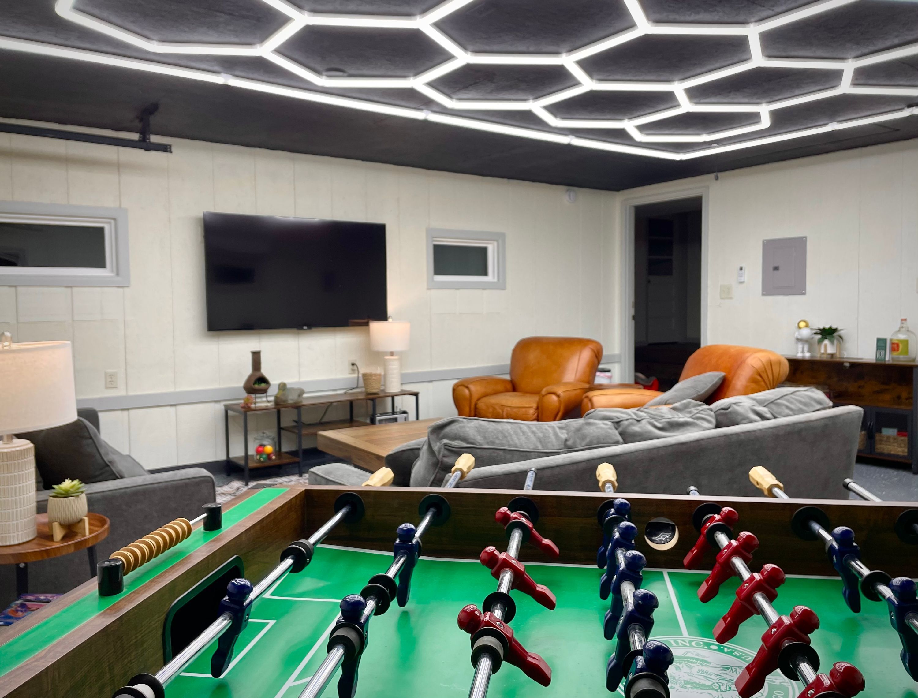 Una sala de estar moderna con una mesa de fútbol de mesa, un televisor de pantalla plana grande y asientos cómodos.