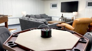 A modern living room with a sectional sofa, a round coffee table, and a leather armchair. - Lake House Kayaks Patio Deck Private Pier (Rome City)