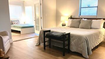 A bedroom with a bed, a chair, a nightstand, and a window with blinds.