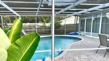 Una piscina con una zona patio coperta, circondata da piante verdi rigogliose.