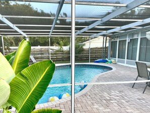 Une piscine dotée d’un patio couvert, entourée de grandes plantes vertes.