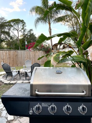 A barbecue grill with four controls, a wooden fence, and outdoor seating. - Sarasota Family Home Private Heated Pool Relax (Sarasota)