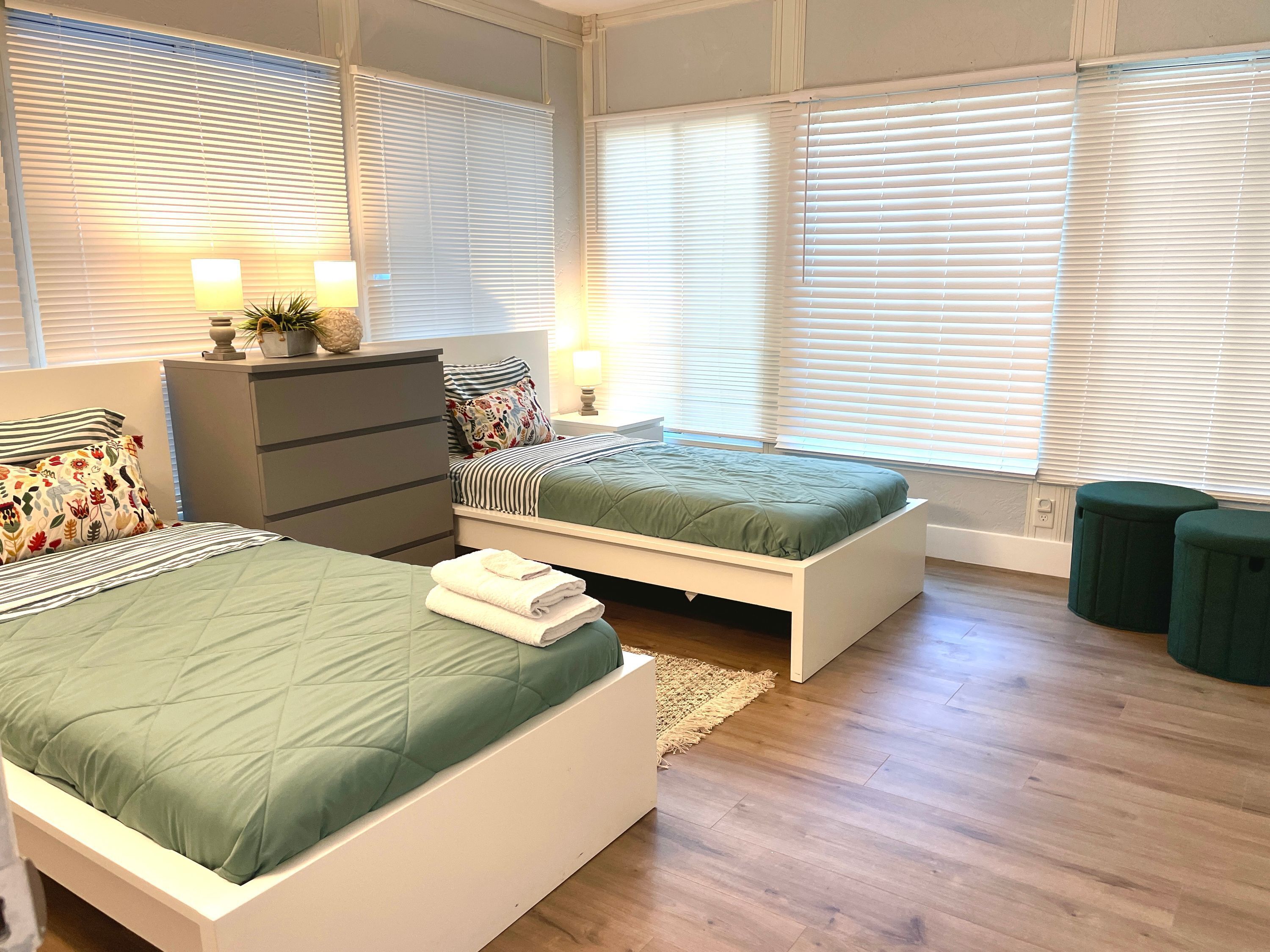Un dormitorio con dos camas, un aparador y una mesita de noche con lámparas.