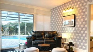 A modern living room with a leather sofa, ottomans, a small round table, and a patterned wall. - Sarasota Family Home Private Heated Pool Relax (Sarasota)