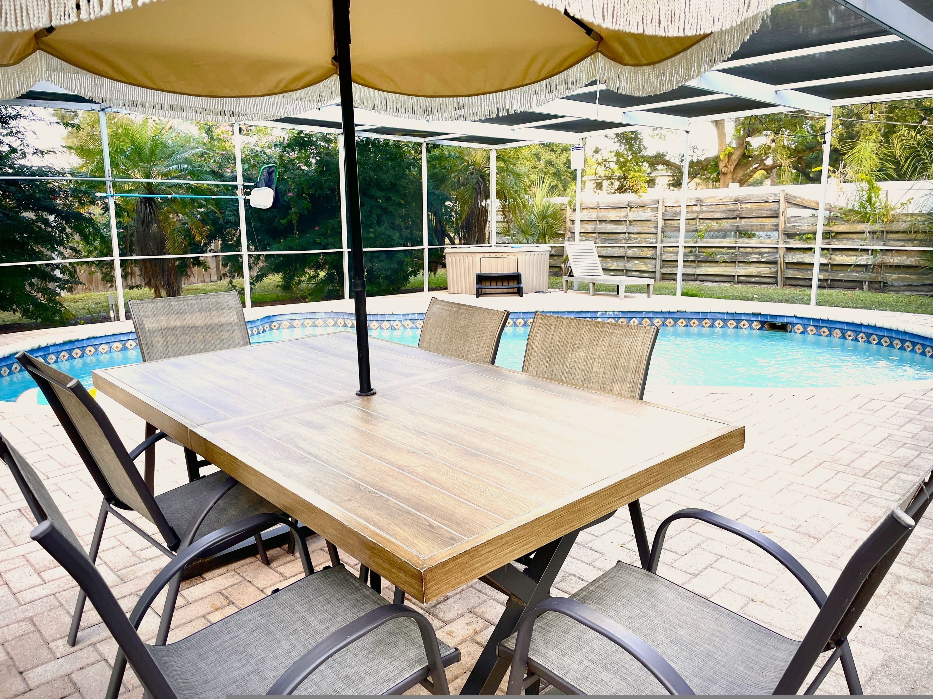 Un espacio al aire libre cubierto con piscina, una mesa y sillas.