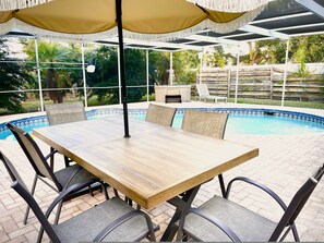 Un espace extérieur abrité comprenant une piscine, une table et des chaises.