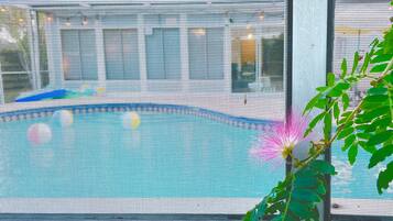 A pool area with a blue pool, surrounded by a fence.