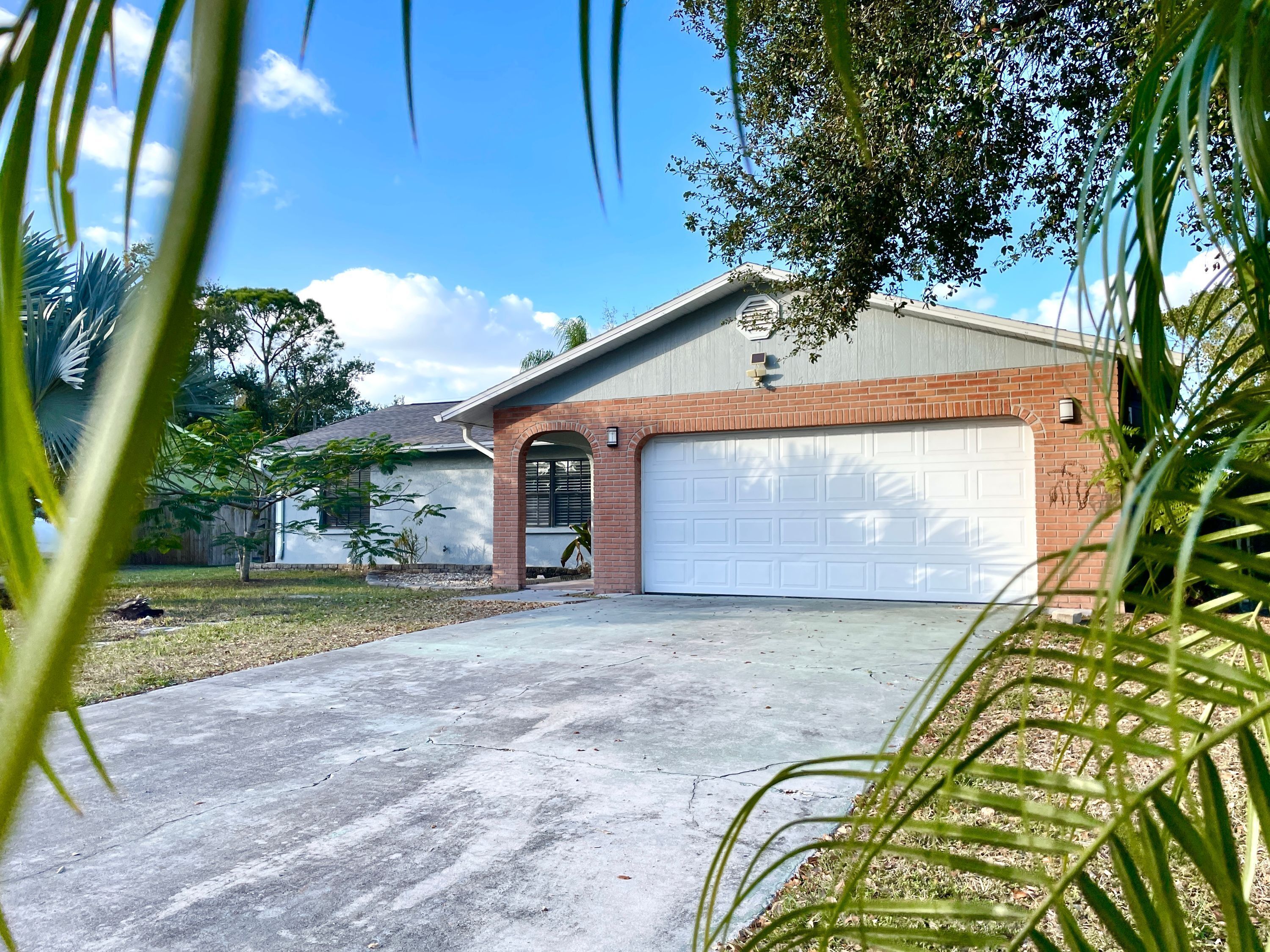 A residential garage with a brick exterior and a white garage door.