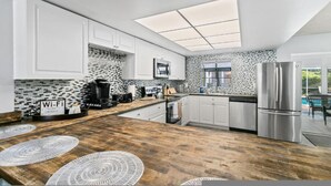 A modern kitchen with white cabinets, a wooden countertop, a built-in microwave, and a stainless steel refrigerator. - Sarasota Family Home Private Heated Pool Relax (Sarasota)